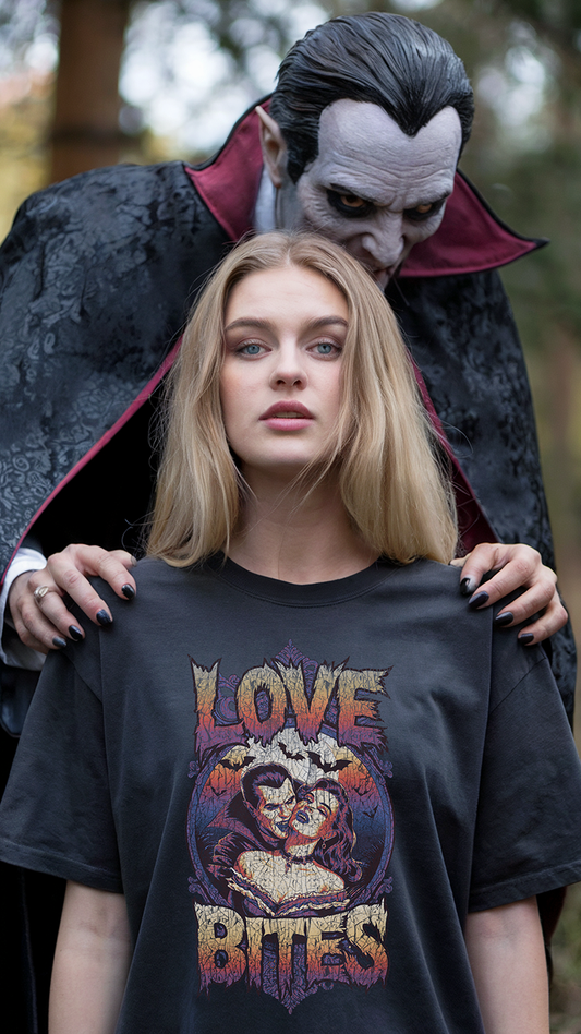 A Young Women Stands in a forest wearing the "Love Bites" Shirt by Twisted Threads Apparel. Dracula is standing behind her about to bit her neck. 